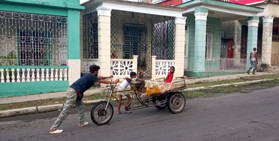 Un trabajador y sus hijos empujan un vehículo cuesta arriba en La Habana.