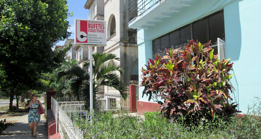 Una mujer camina frente a un Bufete Colectivo en La Habana.