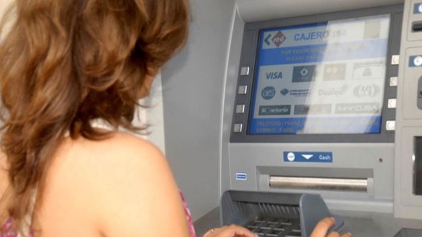 Una cubana extrae dinero en un cajero automático.