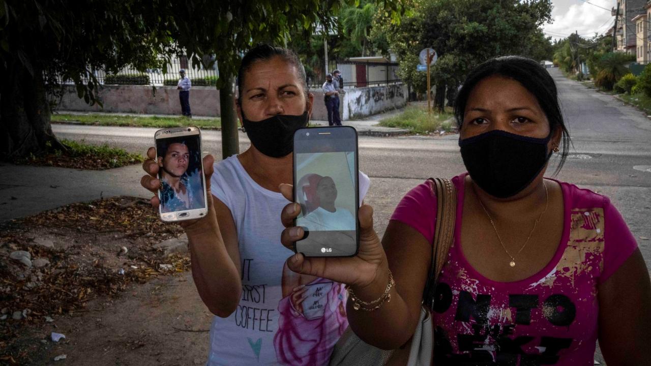 Madres de dos enjuiciados por el 11J muestras fotografías de sus hijos, en La Habana.