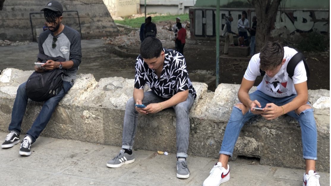 Jóvenes cubanos usan  teléfonos inteligentes para conectarse a internet en La Habana.