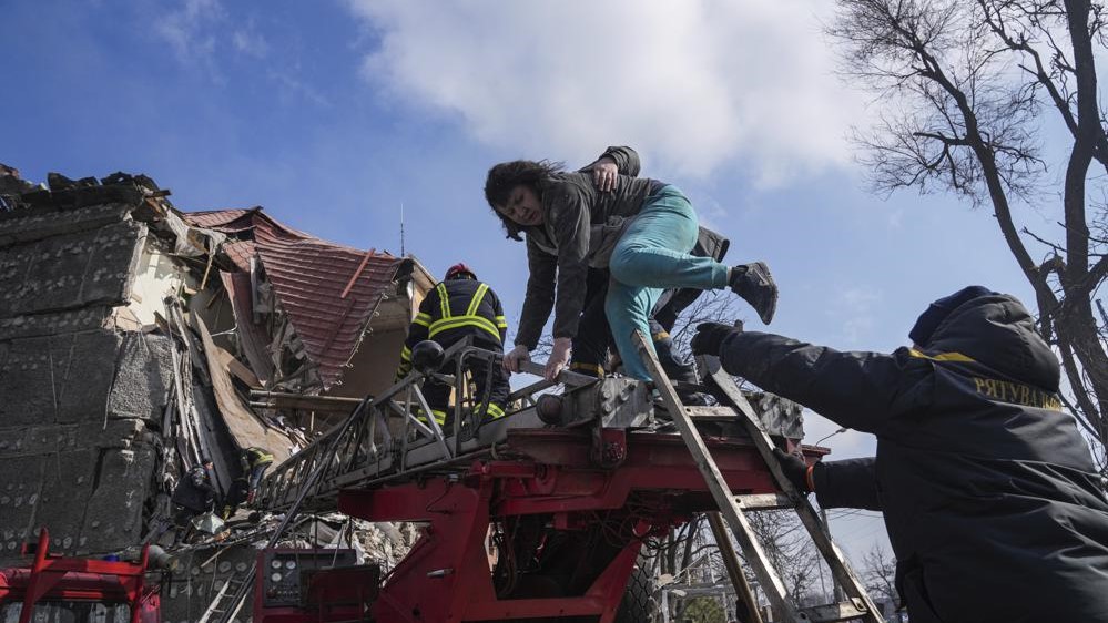 Bomberos socorren a una mujer tras un bombardeo a un edificación en Mariúpol.