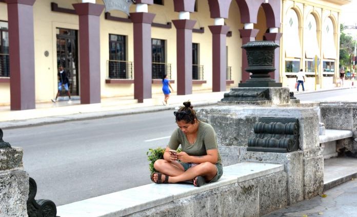 Una cubana consulta su teléfono móvil en el Paseo del Prado de La Habana.