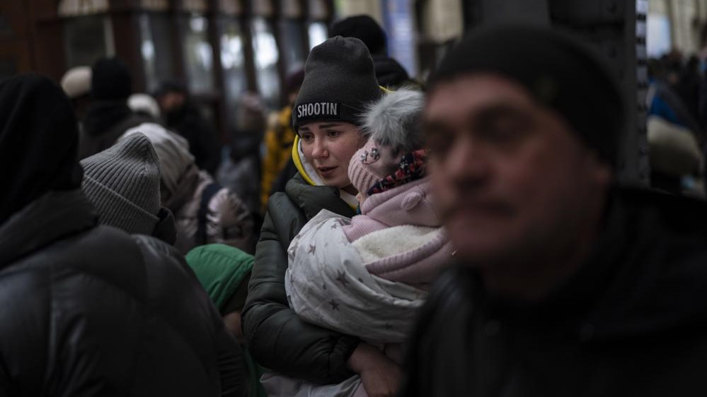 Una familia espera para coger un tren en Leópolis, Ucrania, para escapar de la guerra.