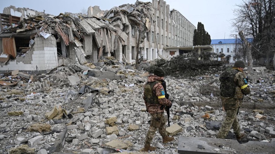 Miembros del ejército ucraniano caminan cerca de un edificio escolar destruido por los bombardeos.