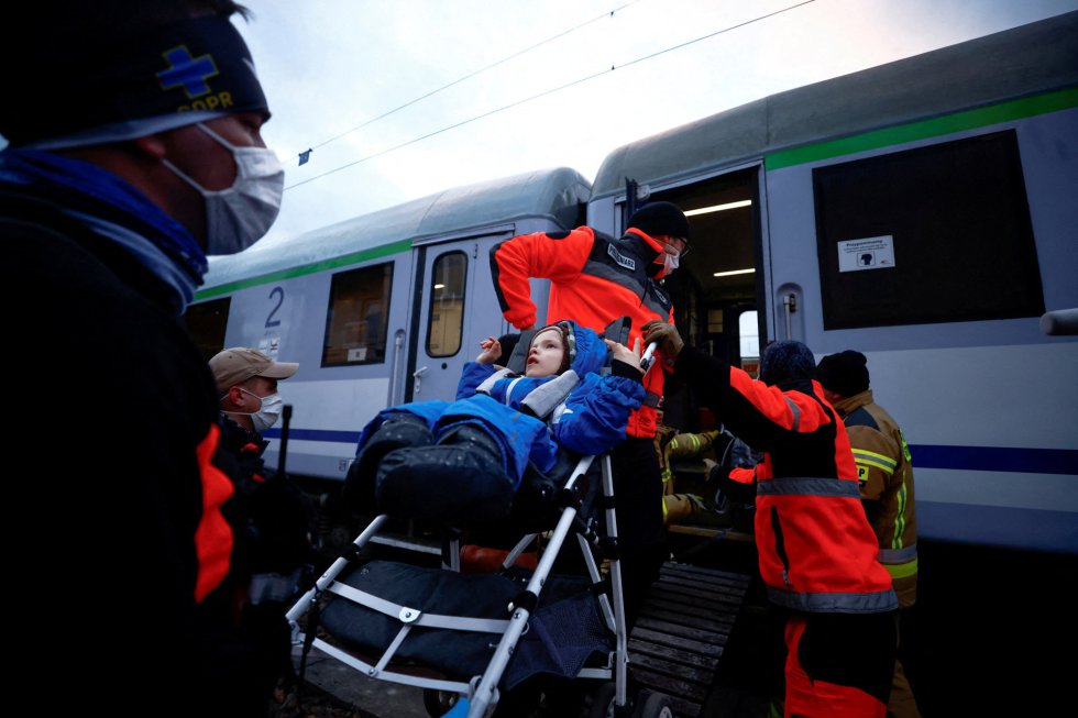 Paramédicos ayudan a un niño evacuado a subir a un tren.