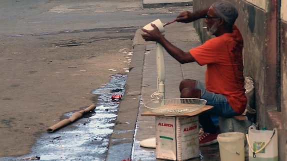 Un anciano arreglando un ventilador en plena calle en La Habana.