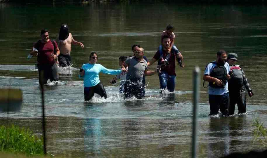 Un grupo de emigrantes con niños cruza el río Bravo.