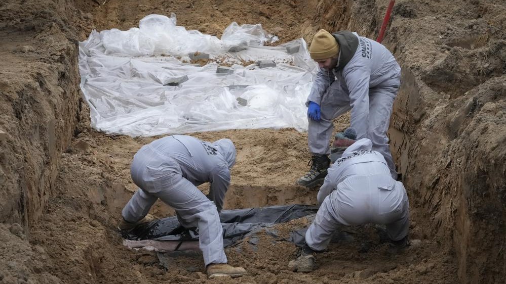 Hombres con equipo de protección exhuman los cuerpos de los civiles asesinados durante la ocupación rusa en Bucha, en las afueras de Kiev, Ucrania, 13 de abril de 2022.