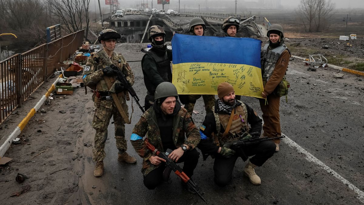 Soldados de Ucrania posan con una bandera.