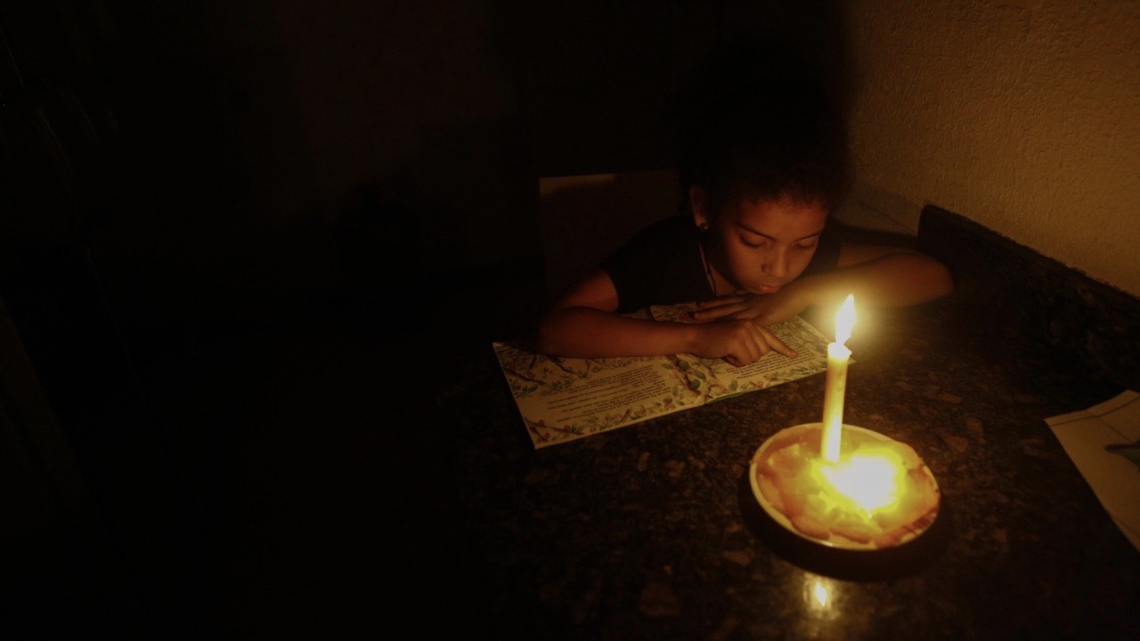 Una niña venezolana lee a la luz de una vela durante un apagón.
