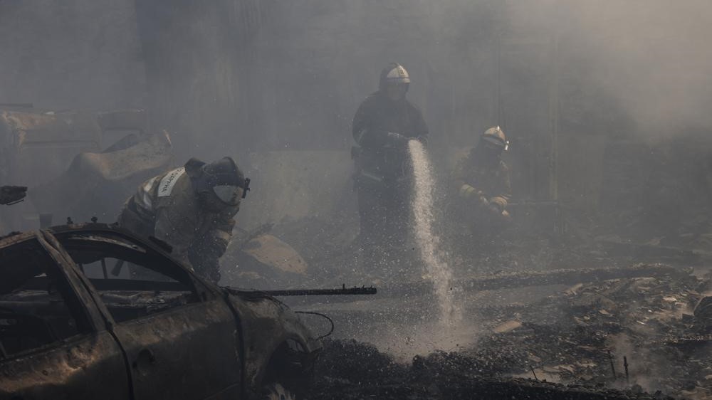 Empleados del Ministerio de Situaciones de Emergencia de Donetsk en la escena de los vehículos quemados después del bombardeo en el distrito de Leninsky, el lunes 6 de junio de 2022.