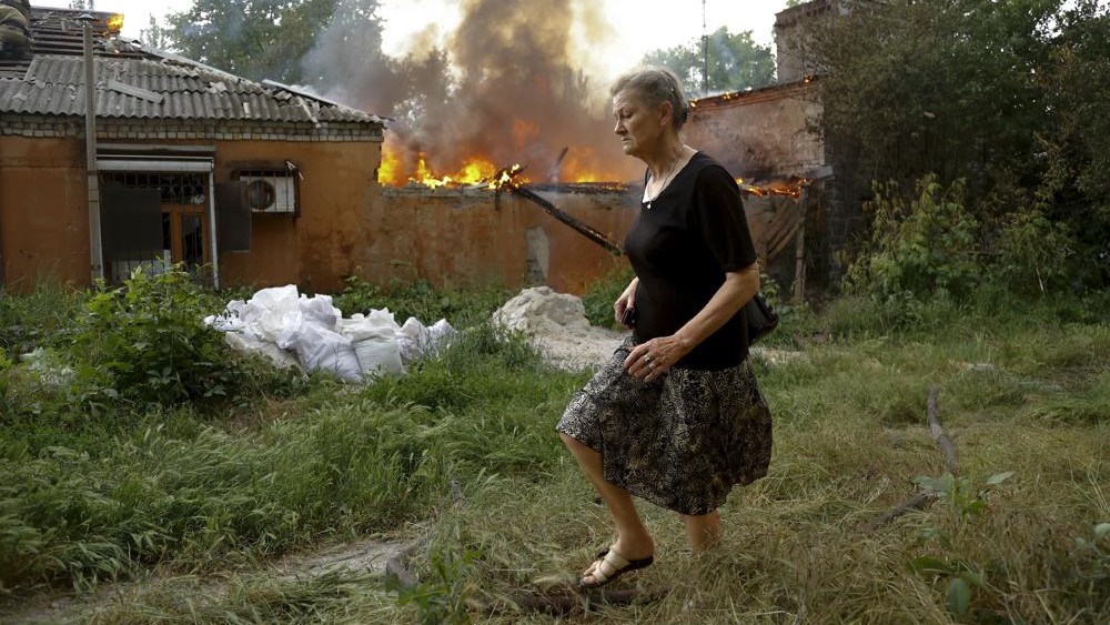 Una mujer sale corriendo de una casa en llamas después de un bombardeo en Donetsk, territorio bajo el control de separatistas prorrusos, viernes 3 de junio de 2022.