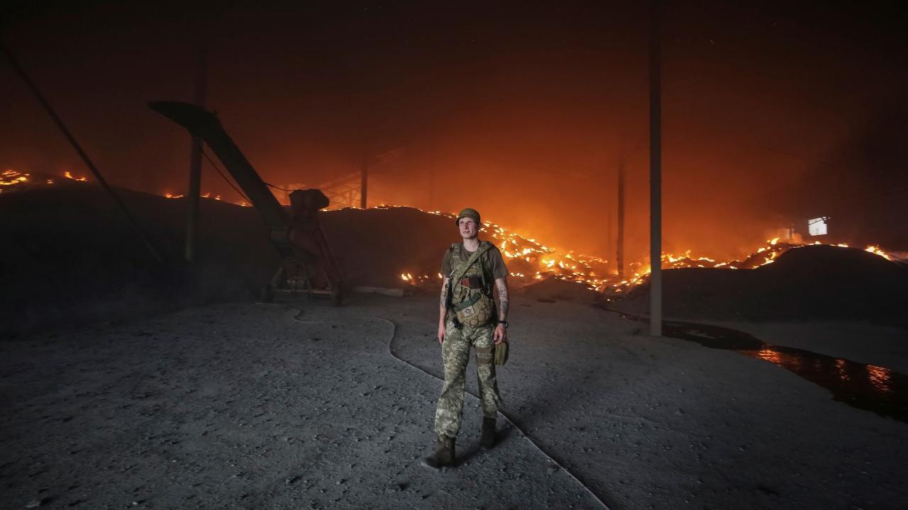 Un militar ucraniano camina mientras las semillas se queman en un silo de grano bombardeado repetidamente en la región de Donetsk, Ucrania, el 31 de mayo de 2022. 