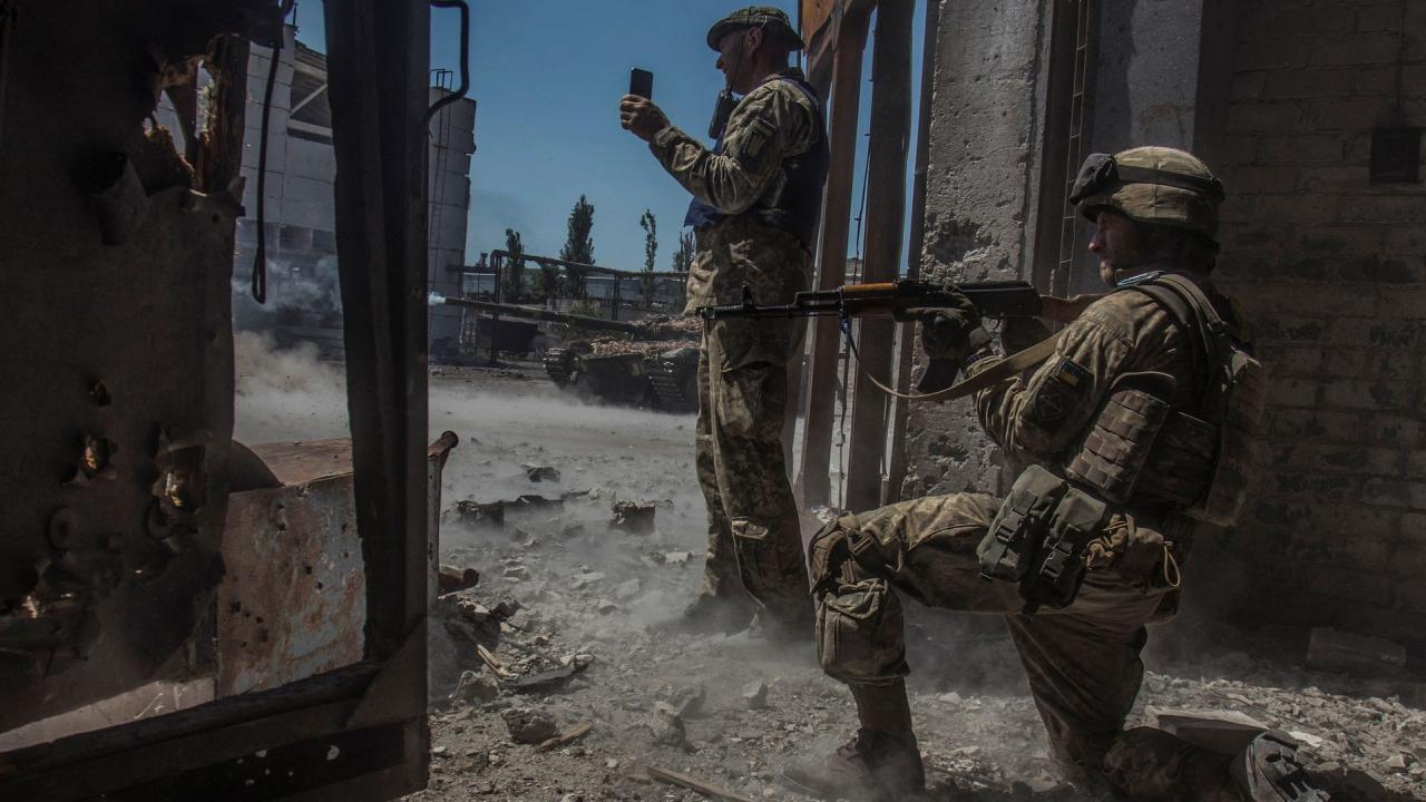 Soldados ucranianos observan mientras un tanque dispara contra las tropas rusas en la zona industrial de la ciudad de Severodonetsk, ucrania, 20 de junio.
