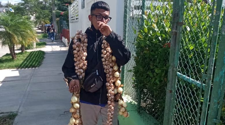 Un joven con ristras de ajo y cebolla en La Habana.
