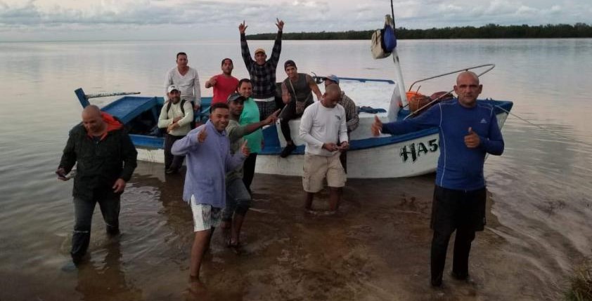 El pelotero retirado cubano Abel Viego Montano (de azul) junto a sus compañeros y la embarcación que compró.