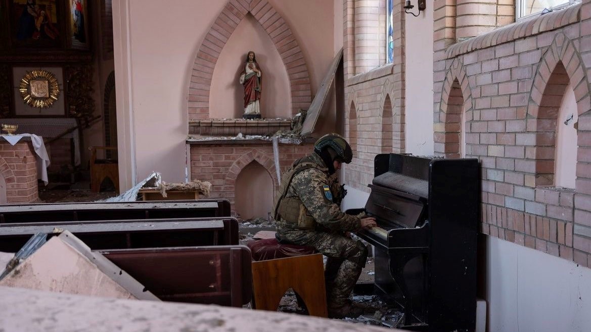 Un soldado ucraniano se sienta al piano de una iglesia impactada por los ataques rusos.