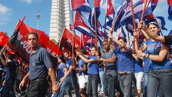Jóvenes agitan banderas cubanas.