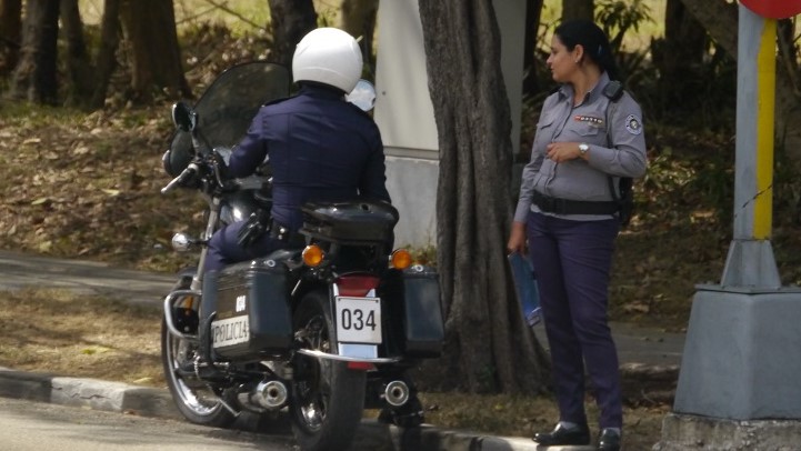 Un policía en una moto-patrulla conversa con una colega. 