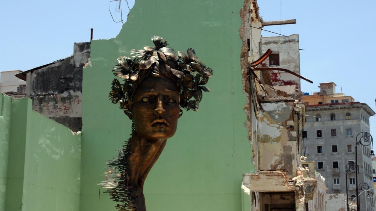 Un grafiti con rostro de mujer en una pared medio destruida de La Habana.