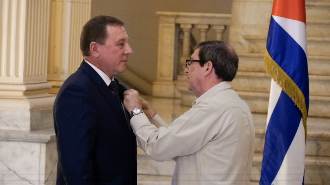El canciller cubano Bruno Rodríguez condecora al embajador ruso Andrei Anatolevich Guskov.