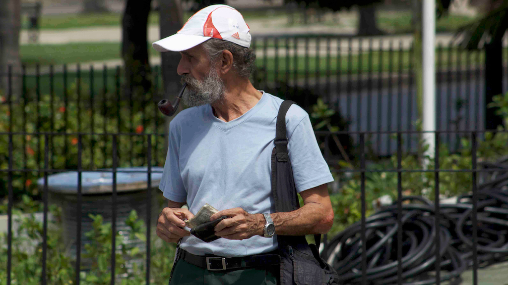 Un hombre en La Habana saca dos pesos cubanos para pagar el transporte público.