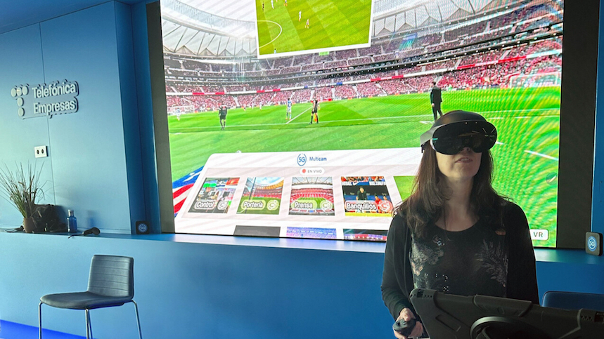 Mujer mira un partido de fútbol de manera remota como si estuviera en el estadio.