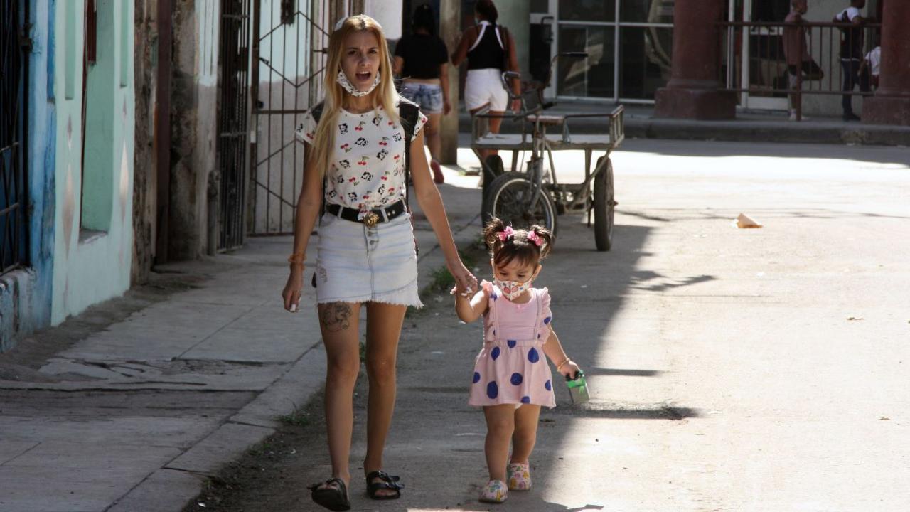 A young Cuban mother and her daughter walk down a Havana street.