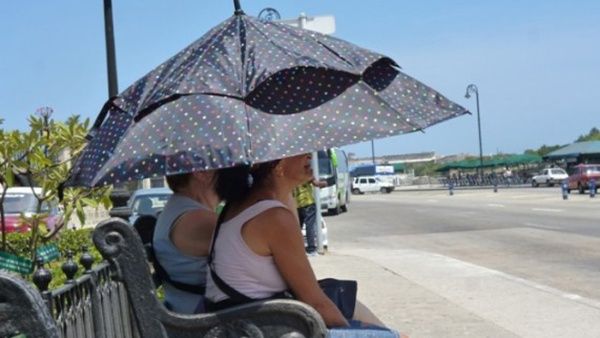 Mujeres protegiéndose del sol en el Malecón de La Habana.