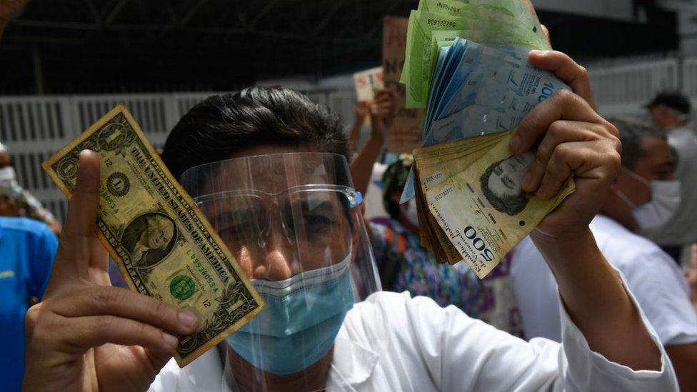 Un venezolano con un dólar en una mano y bolívares en la otra.