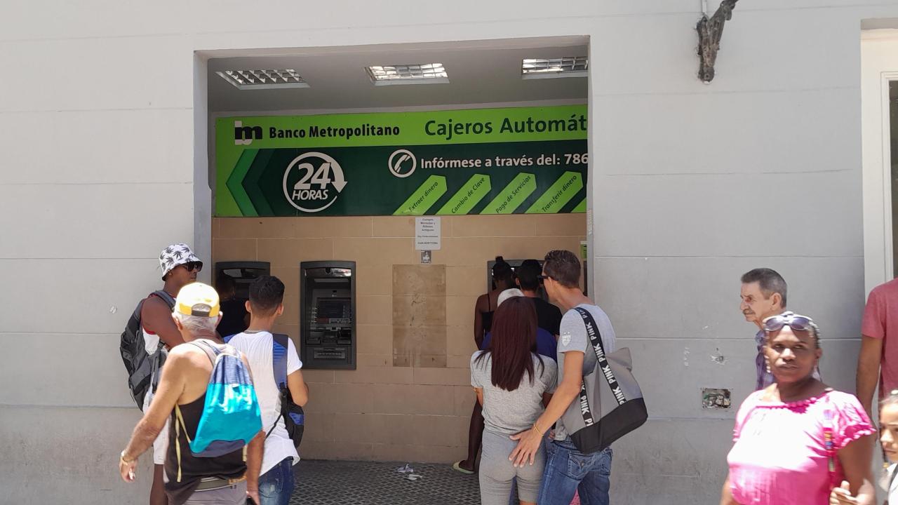 Personas a la espera para usar cajeros automáticos en un banco en La Habana.