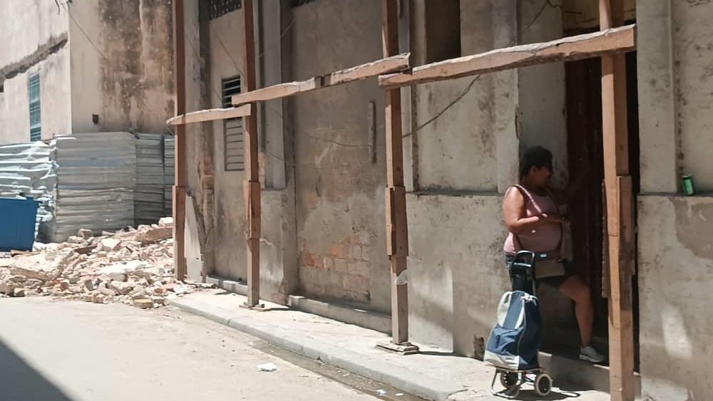 Una mujer en el umbral de un edificio apuntalado en La Habana.