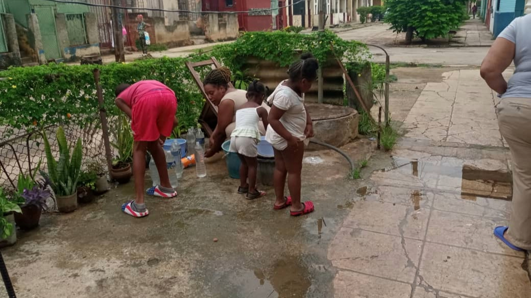 Una familia cubana llena envases de agua.