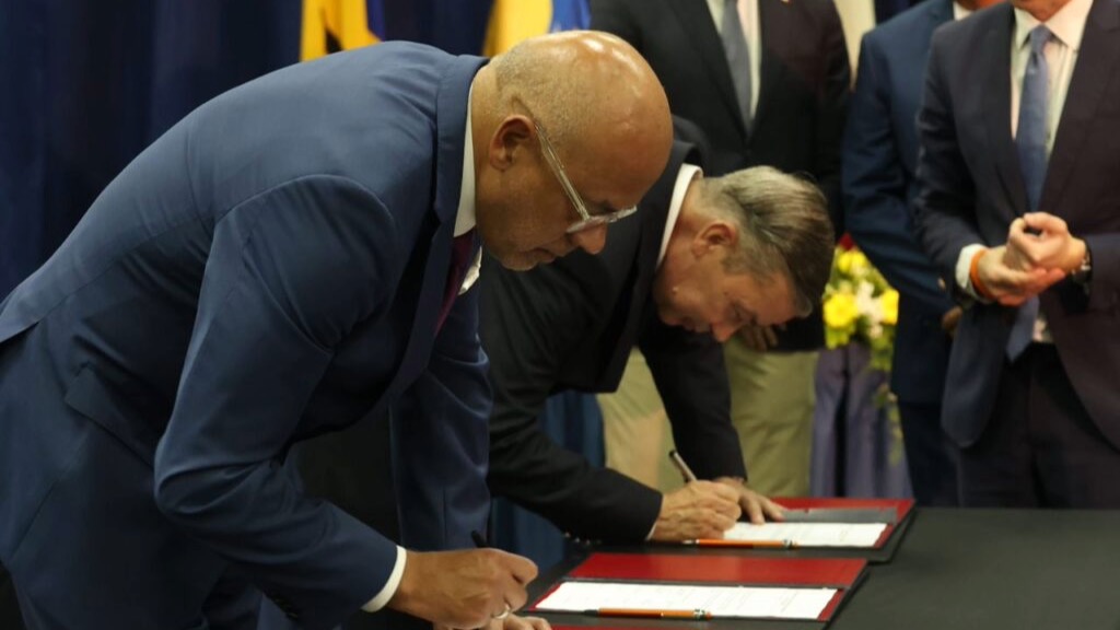 Jorge Rodríguez (chavismo, izq.) y Gerardo Blyde (oposición) firman acuerdos en Barbados.