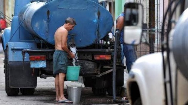 Un cubano cargando agua en cubos de un camión pipa en La Habana.