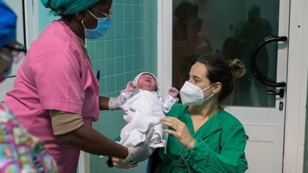 Una enfermera entrega a una madre su bebé recién nacido.