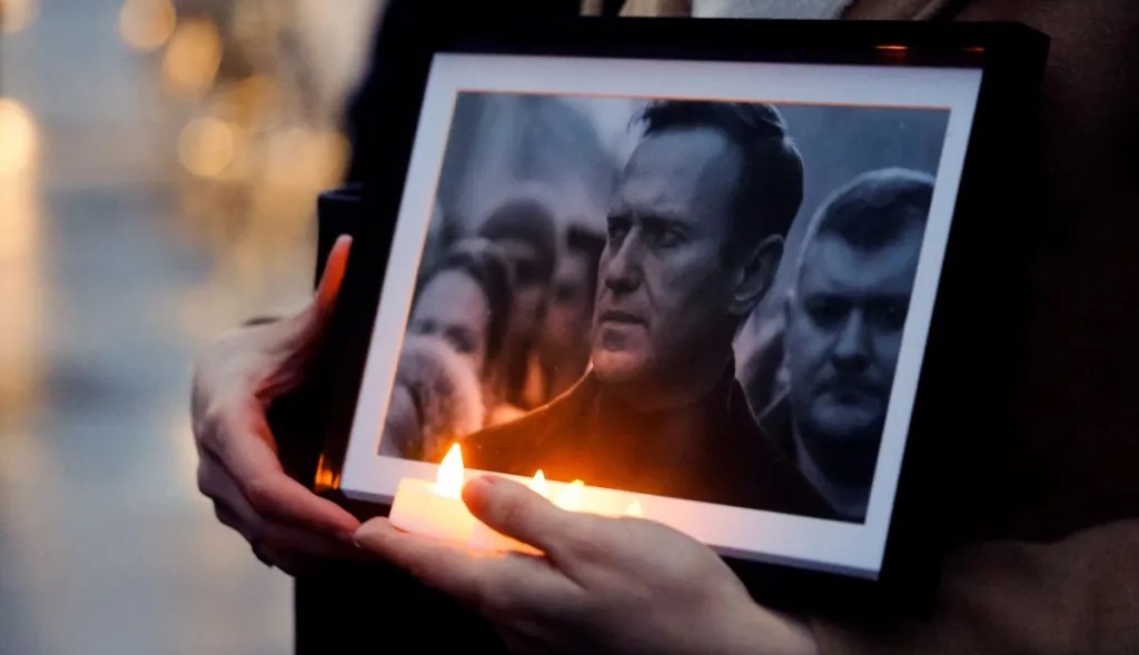 Un manifestante sosteniendo velas y una fotografía de Alexei Navalni en París.