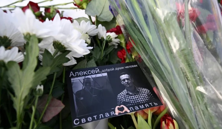 Una tarjeta con imágenes de Alexéi Navalni, colocada en un monumento de Moscú.