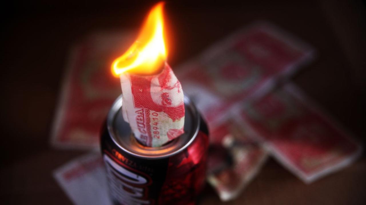 Un billete de peso cubano arde en medio de un apagón.