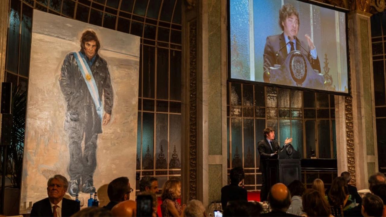 El retrato del presidente argentino, Javier Milei, a la izquierda, mientras él da un discurso.
