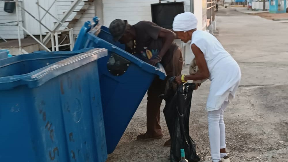 Dos ancianos revisan un depósito de basura en La Habana.