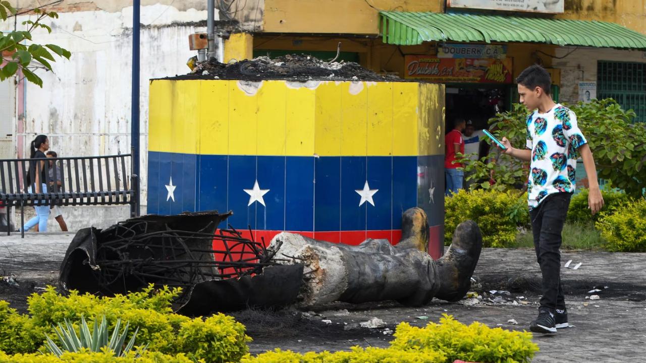 Una estatua destruida de Hugo Chávez yace junto a su base en Valencia, Venezuela.