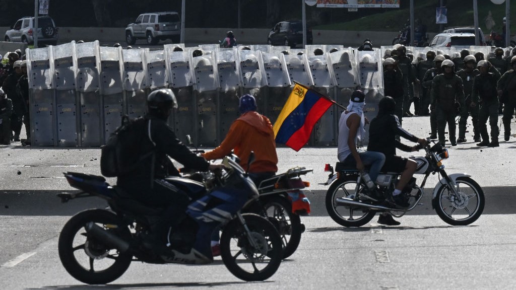 Manifestantes en motocicletas frente a miembros de la Guardia Nacional Bolivariana durante una protesta en Caracas.