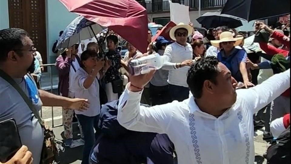 Momento en el un manifestante lanza una botella contra AMLO.