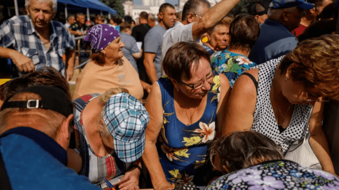 Ciudadanos rusos evacuados de la región de Kursk hacen cola en un centro de distribución de ayuda humanitaria.