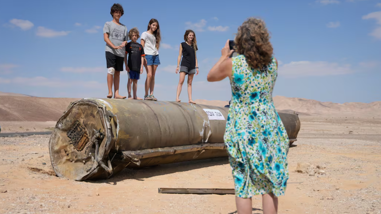 Niños se toman una foto sobre los restos de un misil iraní derribado sobre Israel.