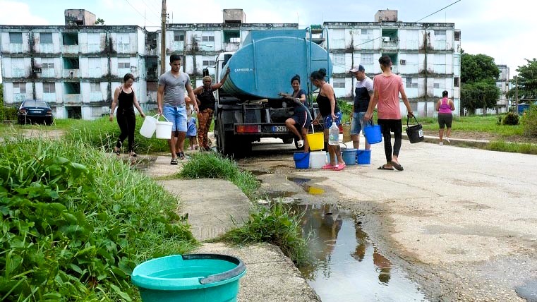 Personas en un barrio de La Habana llenan cubos de agua.