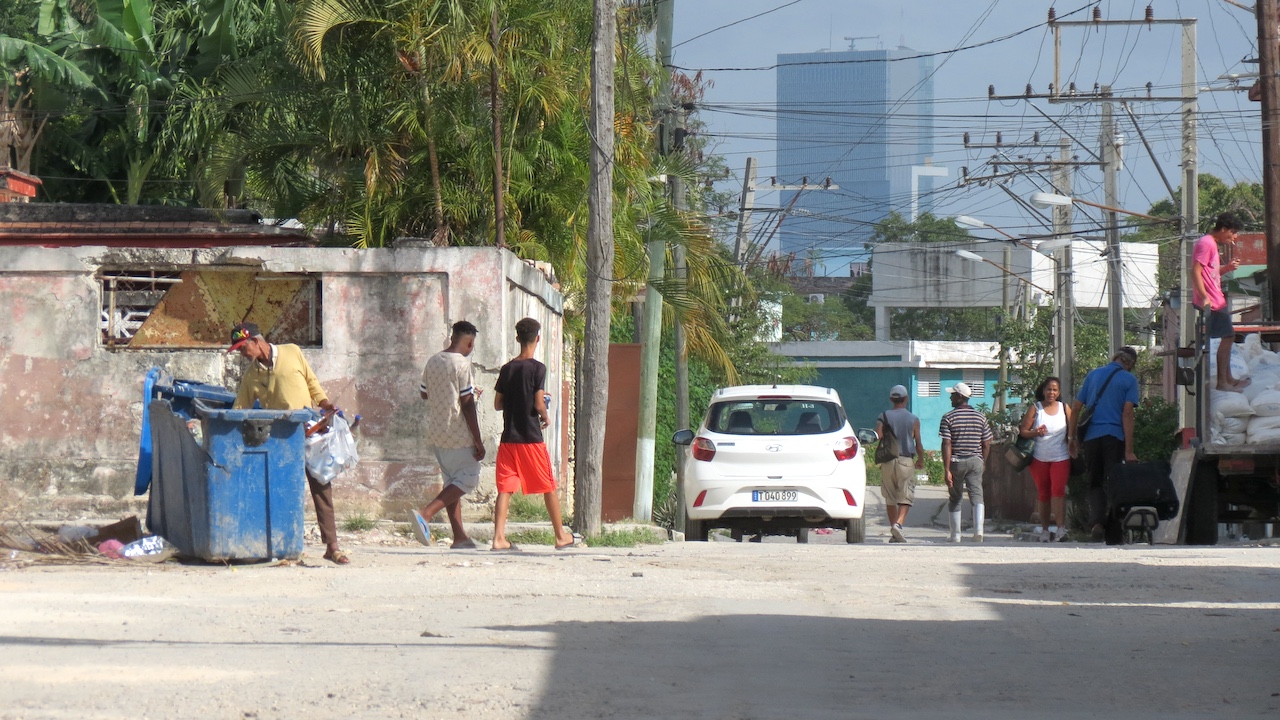 Un hombre busca en un contenedor de basura en La Habana. Al fondo, la Torre K de GAESA.