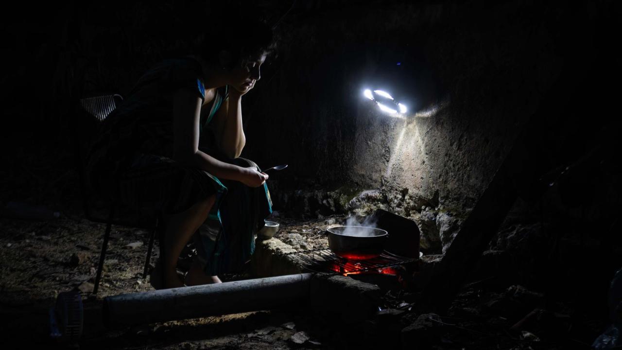 Una cubana cocinando con carbón en medio de un apagón.